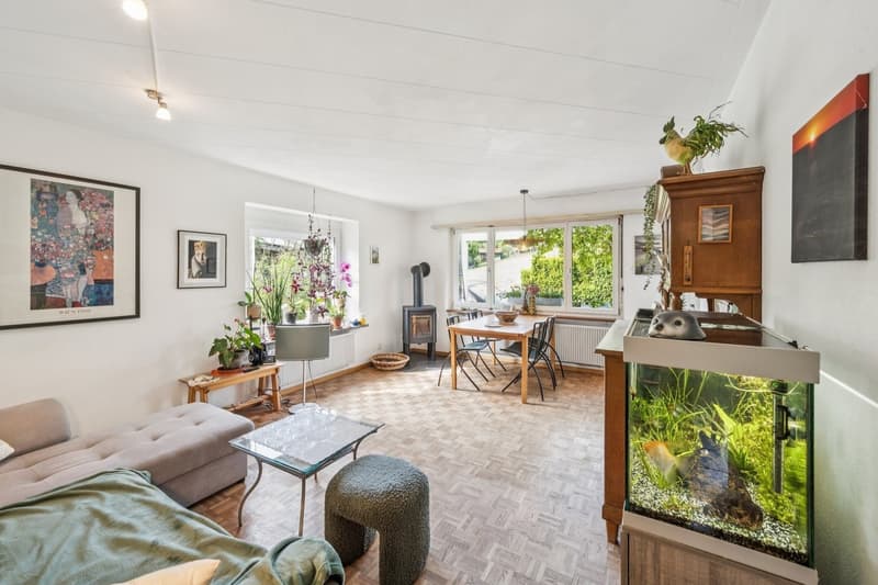 Das helle Wohn- und Esszimmer mit Schwedenofen, Parkettboden und direktem Zugang zum Aussensitzplatz lädt zum Geniessen ein