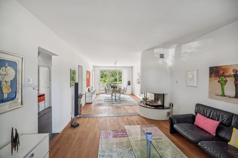 Der offen gestaltete Wohn- und Essbereich mit elegantem Cheminée und direktem Zugang zur Terrasse bildet den Mittelpunkt des Hauses.