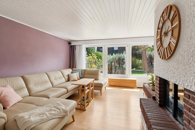 Ein echtes Highlight ist das helle Wohnzimmer mit Cheminée und grossen Fensterfronten zum Garten - Staging