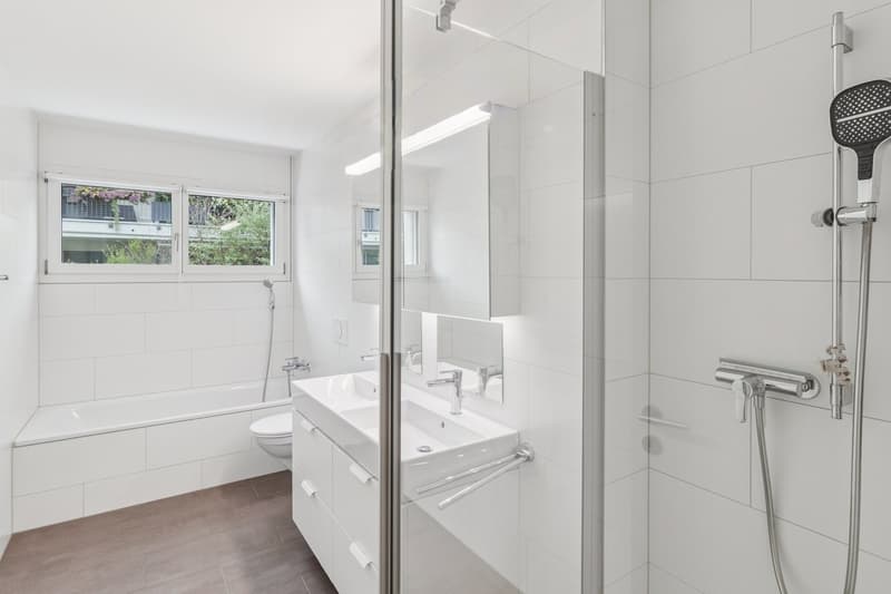 Ein helles Badezimmer mit Dusche, Doppellavabo, Badewanne, das Fenster sorgt für angenehmes Tageslicht.