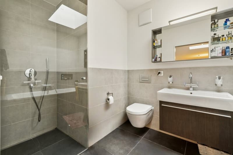 Das Badezimmer verfügt über eine grosszügige Dusche sowie eine Badewanne und überzeugt mit einer hochwertigen Ausstattung in zeitlosem Design.