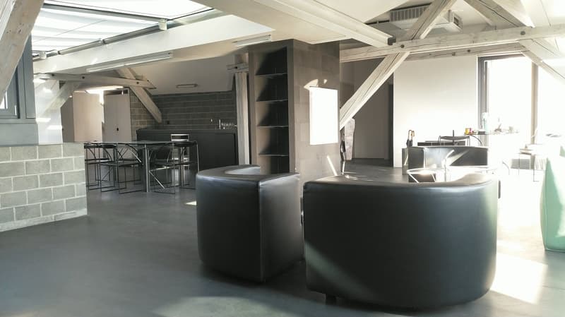 Aerial view of a room with modern furniture, grey walls, high ceilings with wooden beams