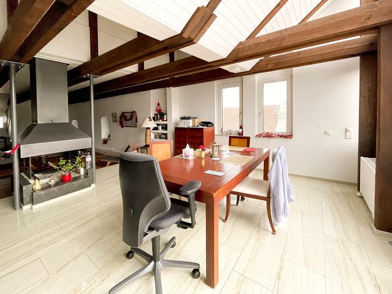 Dining room with dining table and chairs, wooden beams, fireplace with white tiled hearth, white walls and wooden floor