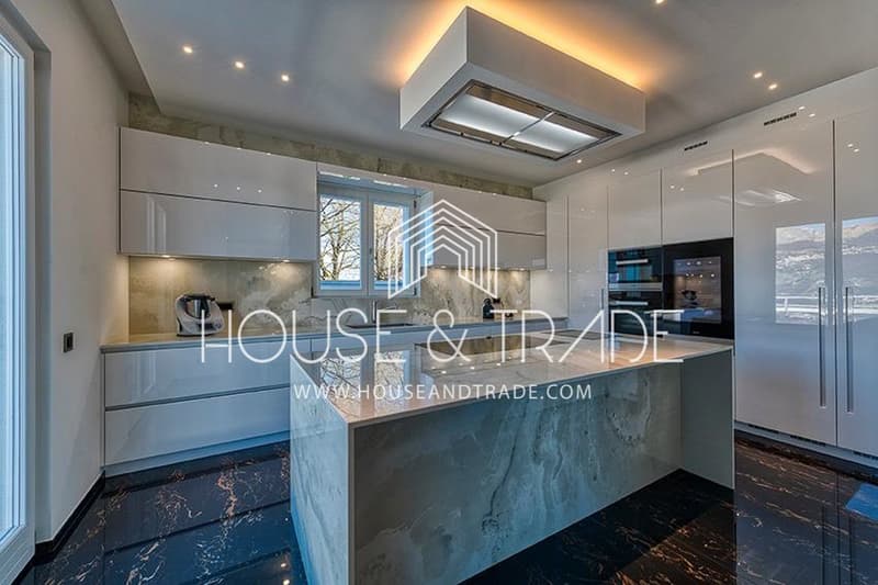 kitchen island, white marble countertop, grey tiled backsplash, built-in oven, extractor hood, cabinets, double-paned windows, glossy marble flooring