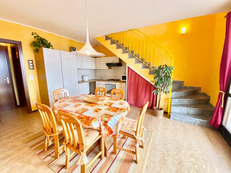 dining area with a table, chairs, cabinets, yellow walls, dining table cloth, stairs, microwave, gas stove, sink, a staircase with handrails, and plants