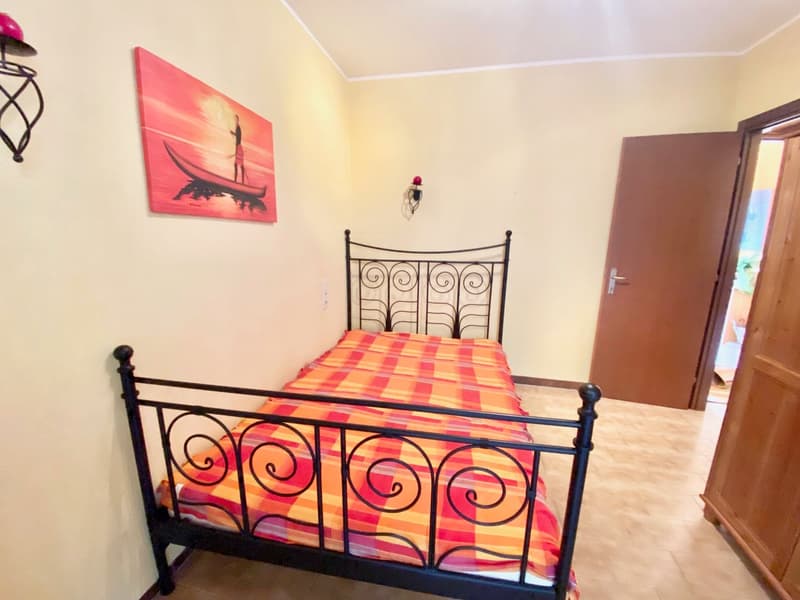 Single bed with decorative headboard, painted wall with picture, wooden door