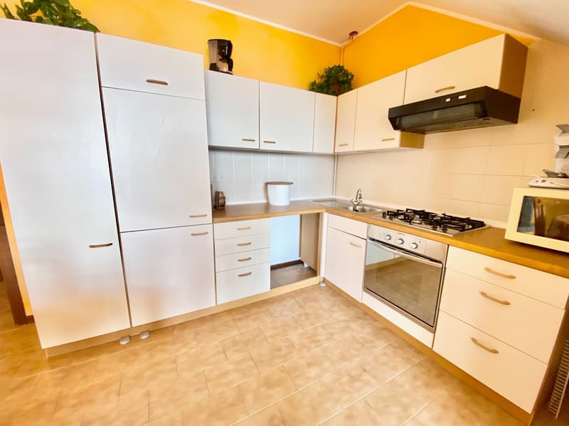 White cabinetry, tiled flooring, gas stove, oven, sink, white refrigerator, wooden countertop, power outlets, microwave