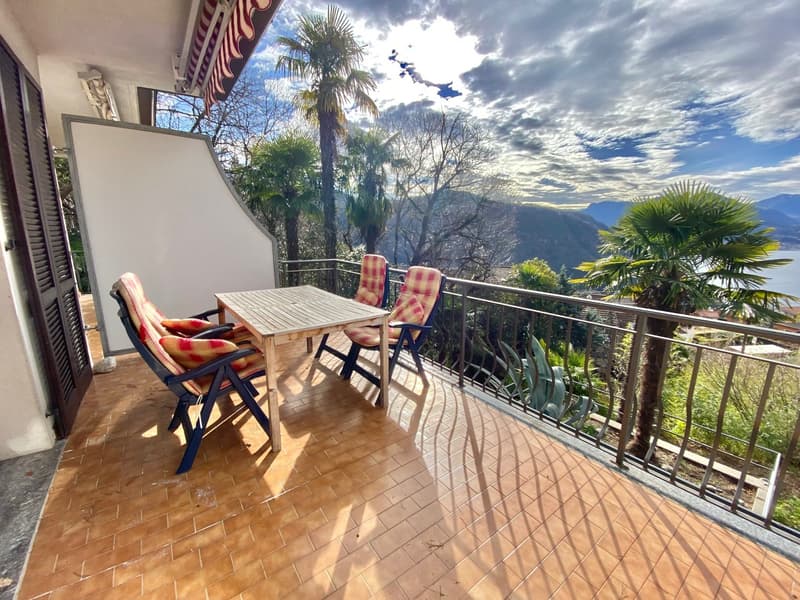 Balcony with table and chairs, tiled floor, metal railing, view of mountains and water