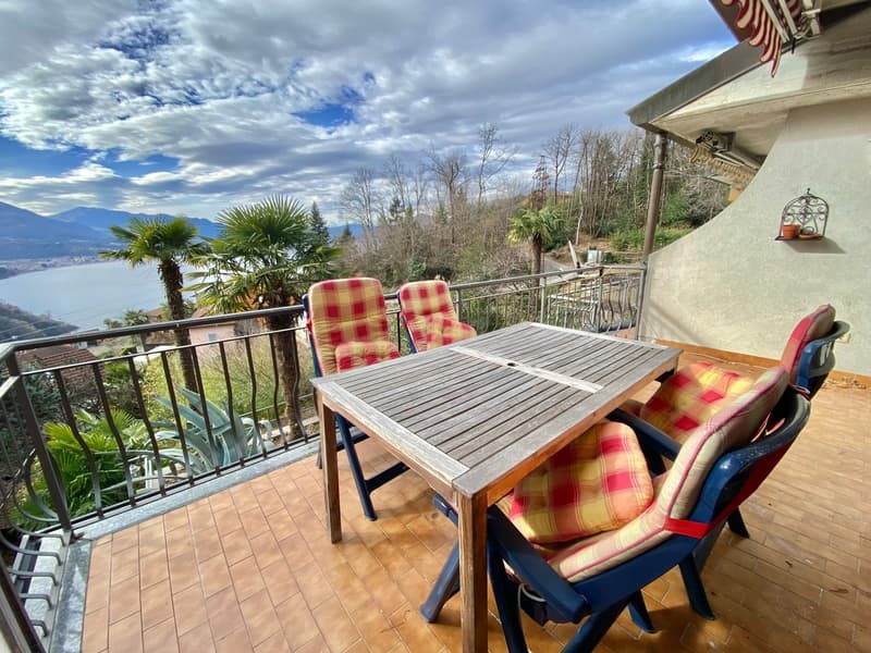 wooden table with 4 chairs, tiled floor, metal railing, view of mountains and lake