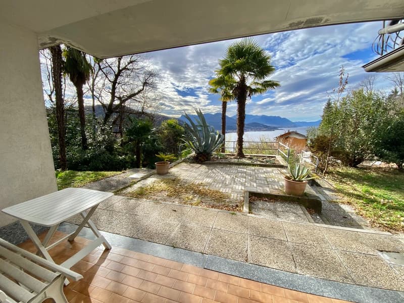 Outdoor patio with tiled floor, small table, chairs, potted plants, and a view of the lake and mountains