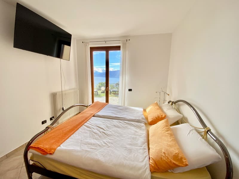 bedroom with a double bed and a large window overlooking a lake