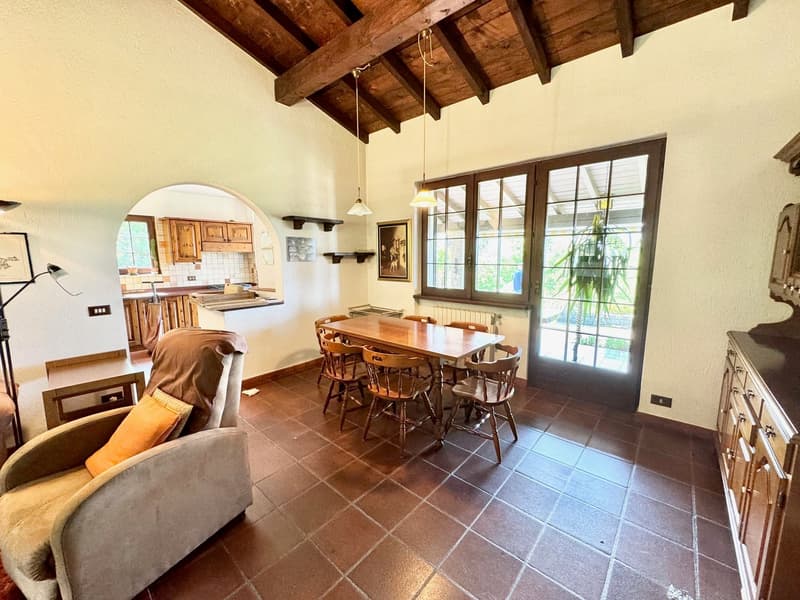 Dining room with table and chairs, kitchen in the background, radiator, brown tiles