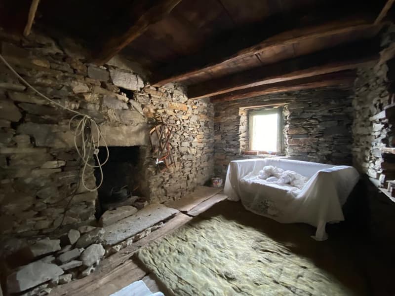 stone walls, wooden beams, fireplace, window, covered bed, rug