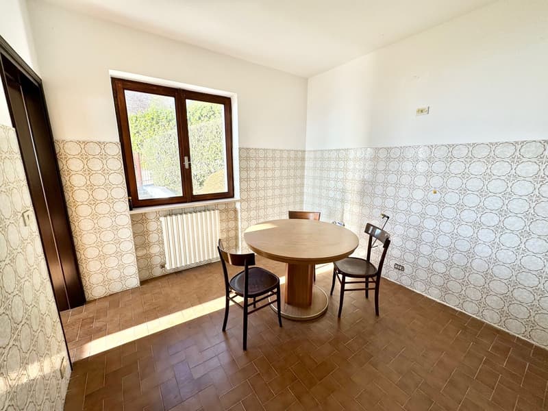 wooden floor, tiled walls, round wooden table, wooden chairs, radiator, window
