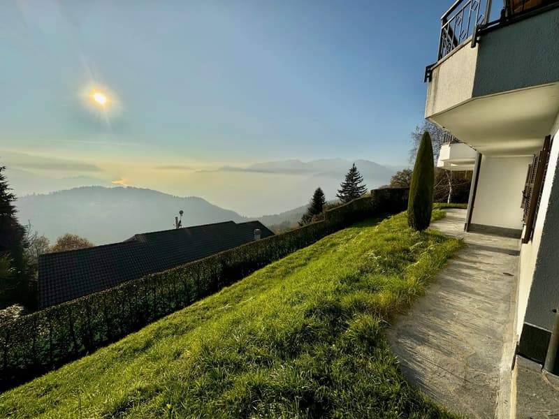 hillside location, grassy slope, pathway, building with balcony, view of mountains and sky