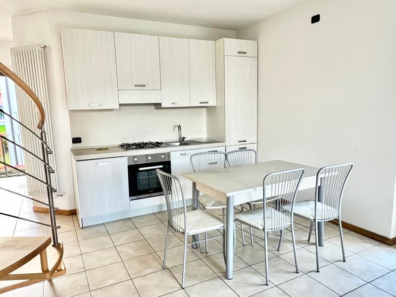Fully equipped kitchen with white cabinets, gas stove, and a dining table with 4 metal chairs