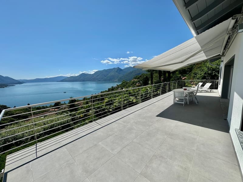 Large balcony or terrace with stunning lake and mountain views, modern tiled flooring, retractable awning, outdoor seating area