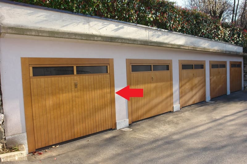 The image shows a row of wooden garage doors with a red arrow pointing to one of the doors.
