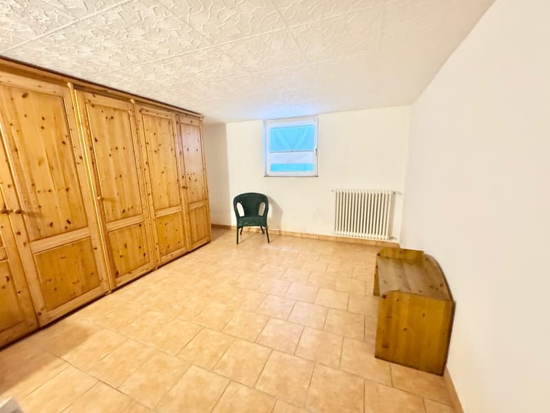 The image shows a room with wooden cabinets/wardrobes along one wall, a tiled floor, and a small window. There is a single green chair in the room.