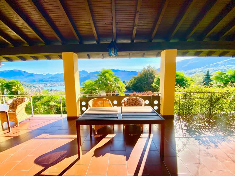 Balcony/Terrace with yellow columns, wooden table with two chairs, iron railings, tile flooring, outdoor setting