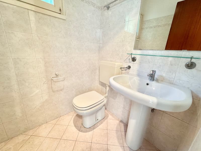 Bathroom with toilet, sink, and mirror on the wall