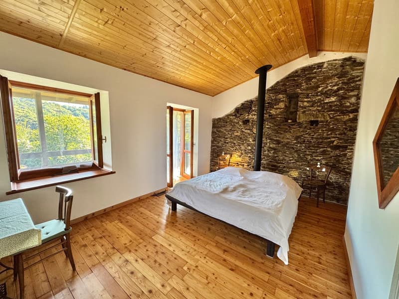 bedroom with bed, wooden floor, wooden ceiling, window with mountain view, fireplace on the wall