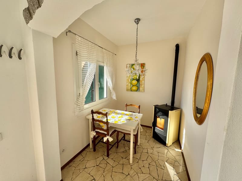 small dining area with a table and chairs, white stone floor, a fireplace with windows