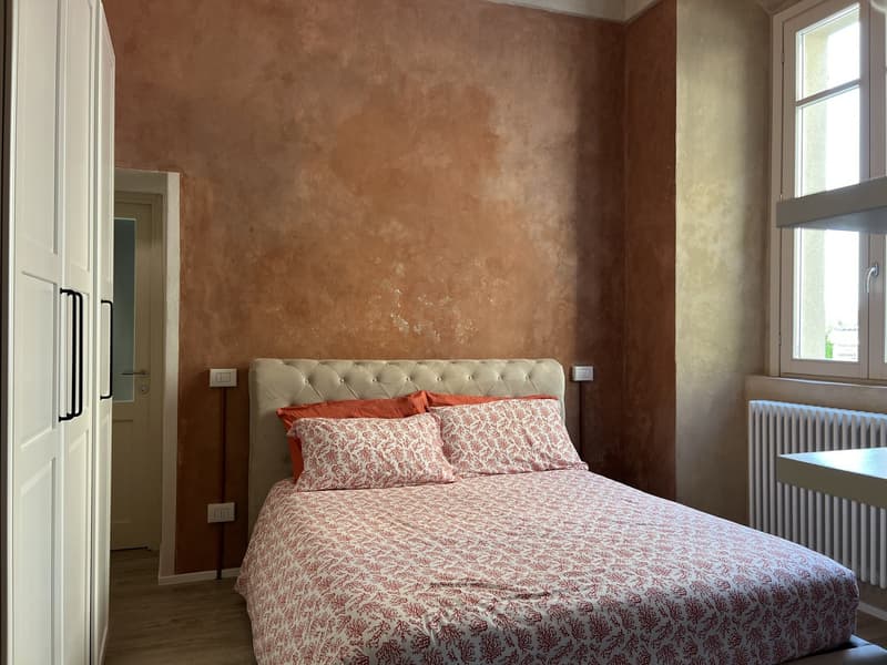 Large bed, pillows, blankets, radiator, double doors, window