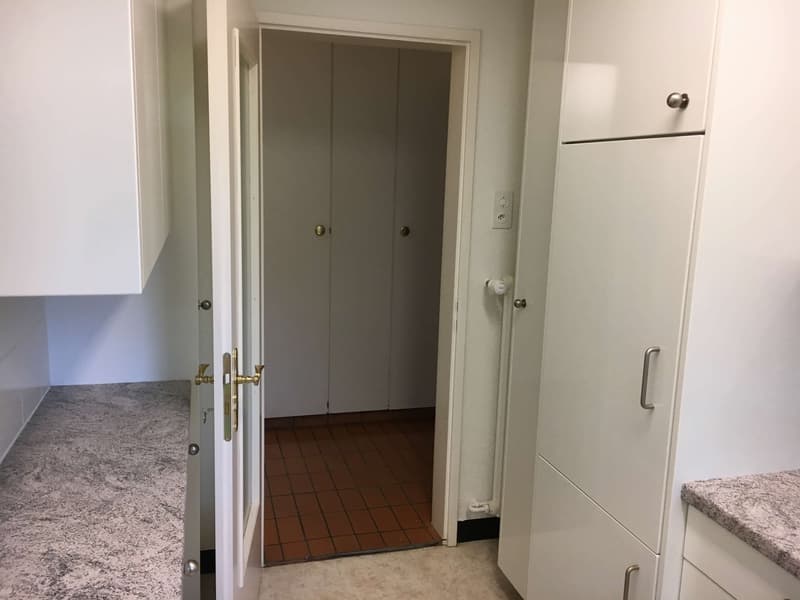 White cabinets, granite countertop, double closet doors, tiled floor