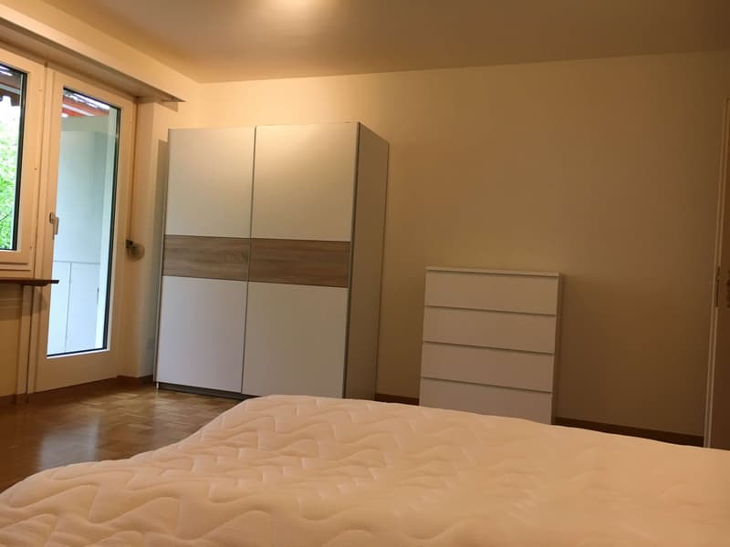 Bedroom with white bed, white wardrobe, white chest of drawers, sliding door, wooden floor