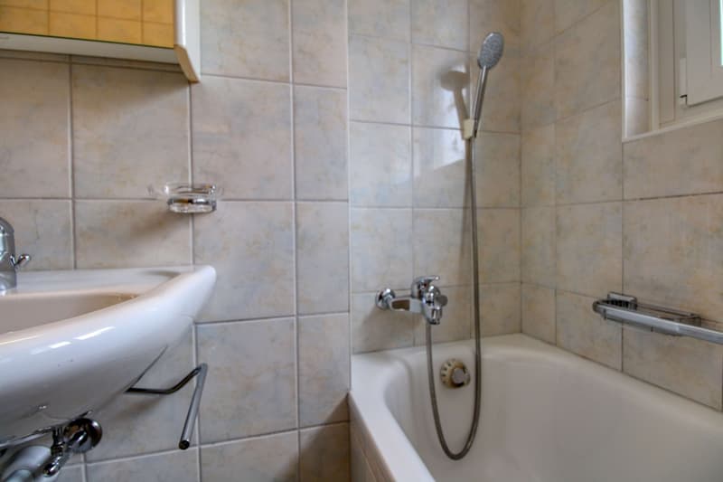Bathtub, sink, shower head, shower handle, tiled walls, mirror, faucet