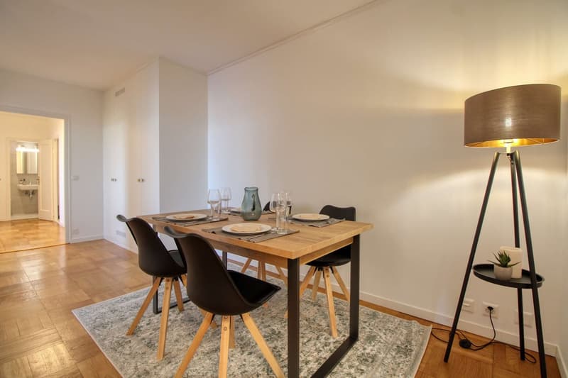 wooden dining table, black chairs, floor lamp, rug, white walls, wooden floor