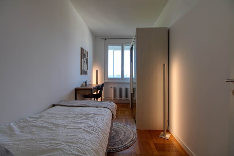 small bedroom with bed, desk, chair, and a window