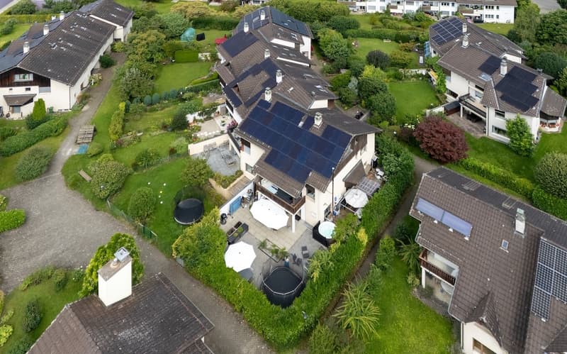 Group of houses with solar panels on the roof, green lawn, pools, and driveways