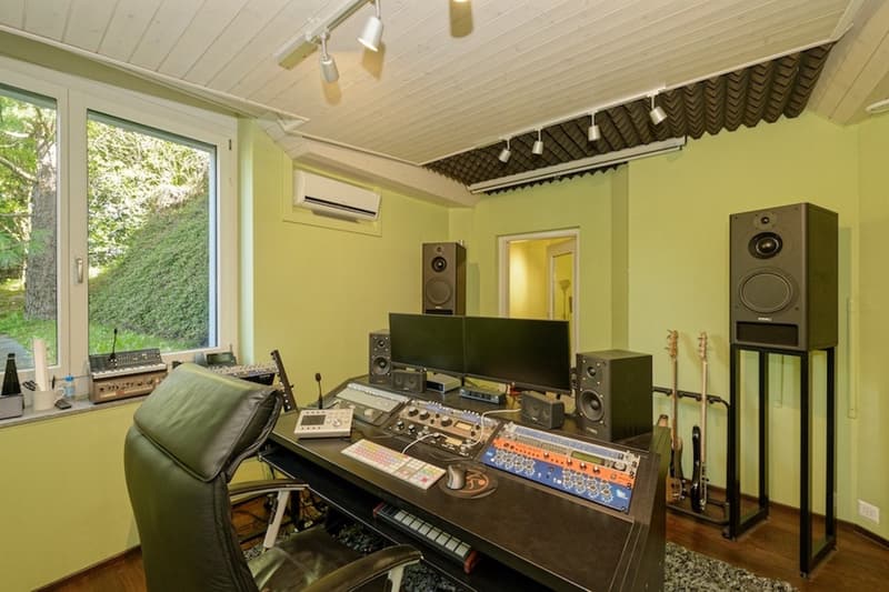 desk with audio equipment, computer monitors, speakers, keyboard, mouse, leather chair, guitars