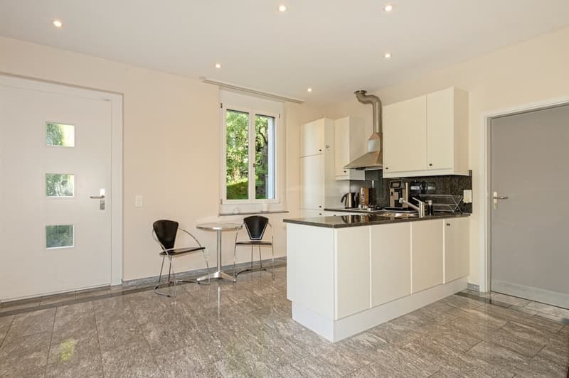 modern open kitchen with island, white cabinets, tiled floor, window with outdoor view, table and chairs