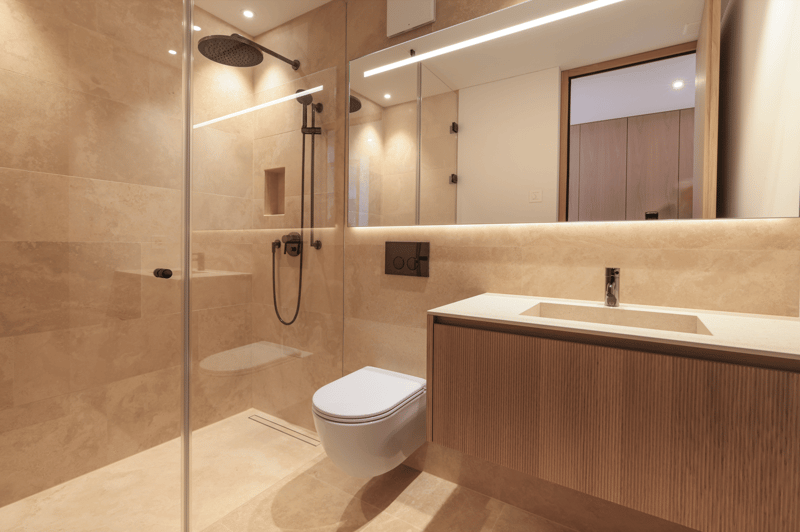 modern bathroom with shower, toilet, sink, mirror, wooden cabinet, beige tiles