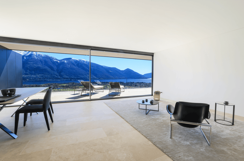 modern living room with large windows, modern furniture, carpet, view of mountains and lake
