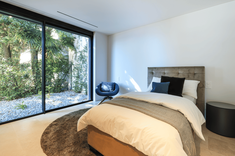 bedroom with large windows, bed, chair, rug, and a view of the garden