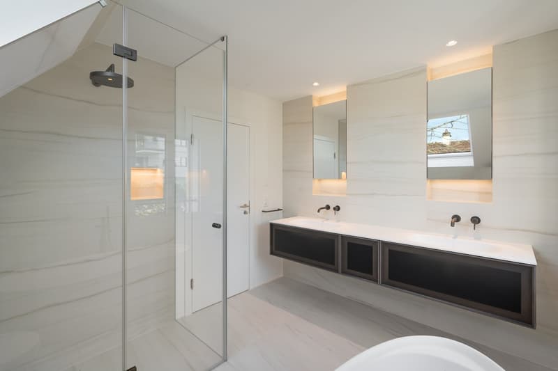 Modern bathroom with glass shower enclosure, large vanity with double sinks, mirrors, and a bathtub.