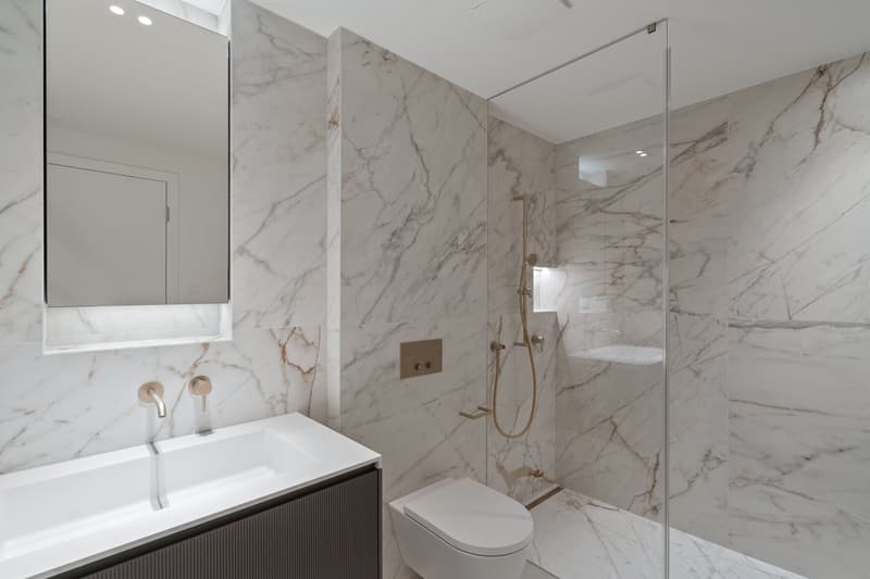 white marble, modern sink, mirror, glass shower, white toilet