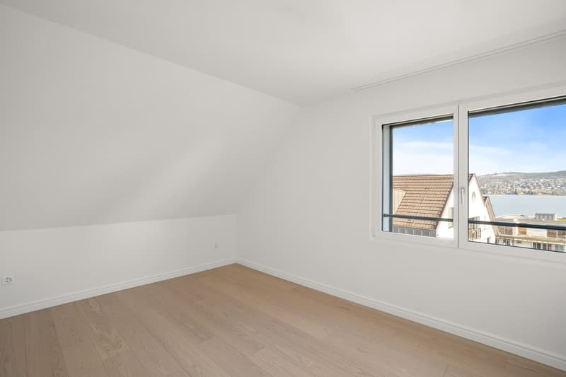 empty room, white walls, wooden floor, large window with view of lake and mountains