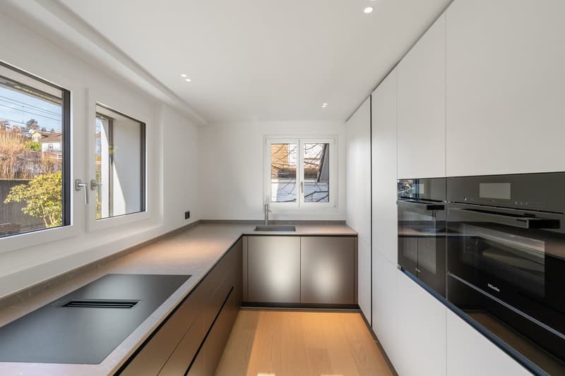 modern kitchen with white cabinets, stainless steel appliances, granite countertops, double oven, sink, and windows