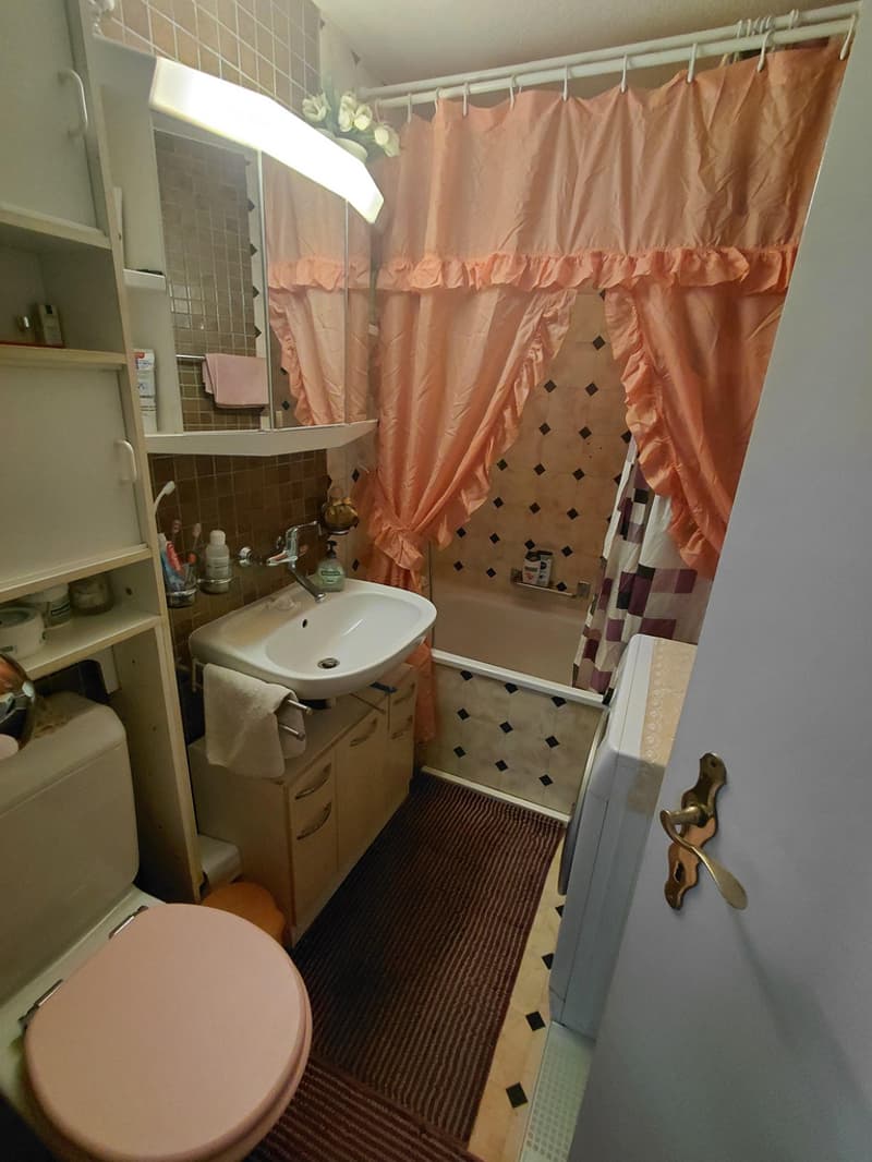 Nasszelle mit Duschbadewanne und Waschmaschine.