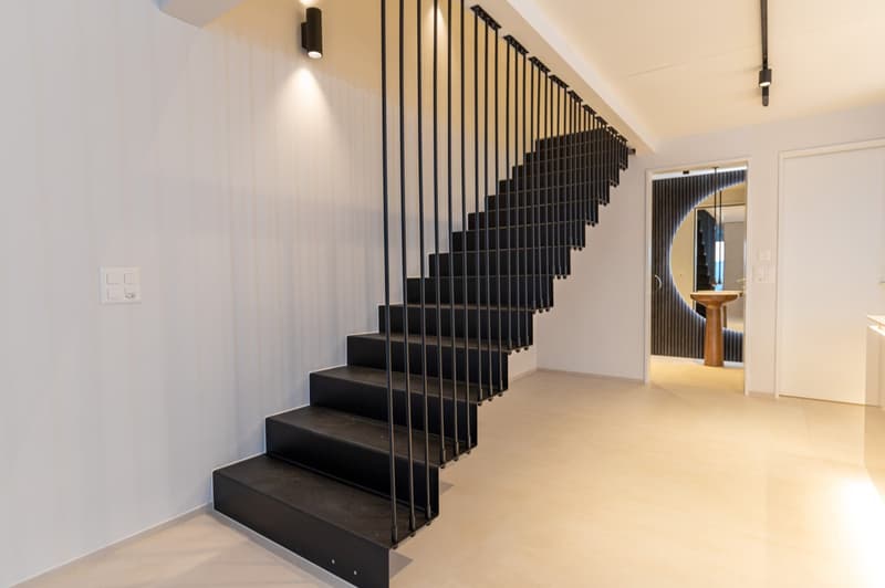 Modern metal staircase with steps and black railings.