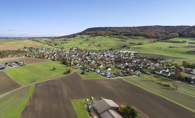 aerial view of village, green fields, hills, clear blue sky