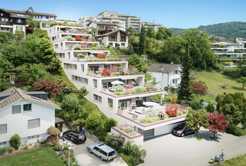 A modern apartment complex situated on the hillside with lush greenery and plants on terraces, multiple cars parked, garage, garden area