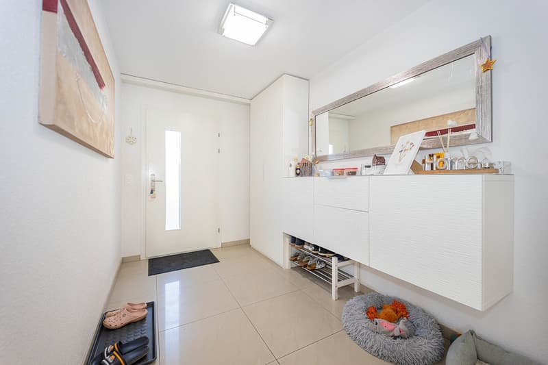Entrance hallway with tiled flooring, built-in shoe storage, entrance mat, and mirror