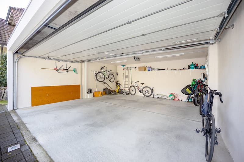 A room featuring multiple bicycles, storage boxes, shovels, cleaning tools, and various other equipment
