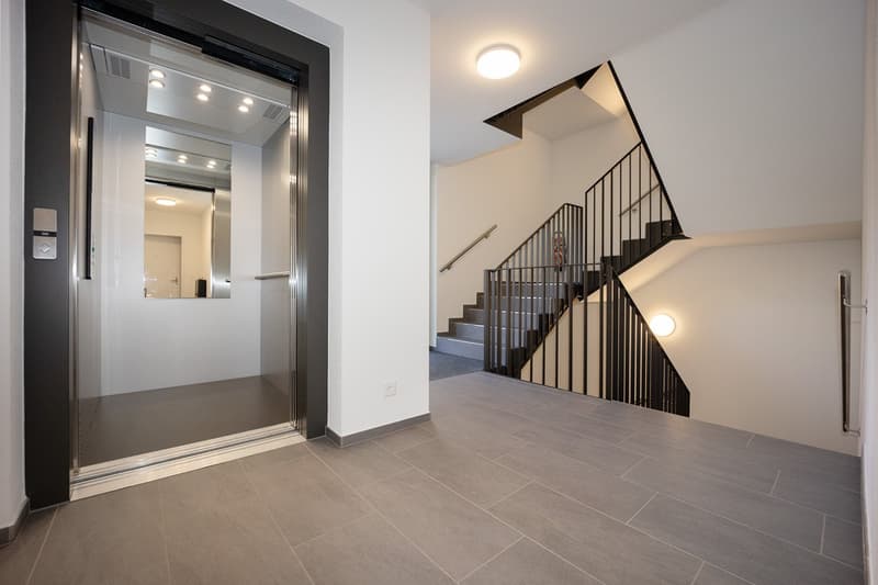 elevator, stairs, tiled floor, white walls, ceiling lights